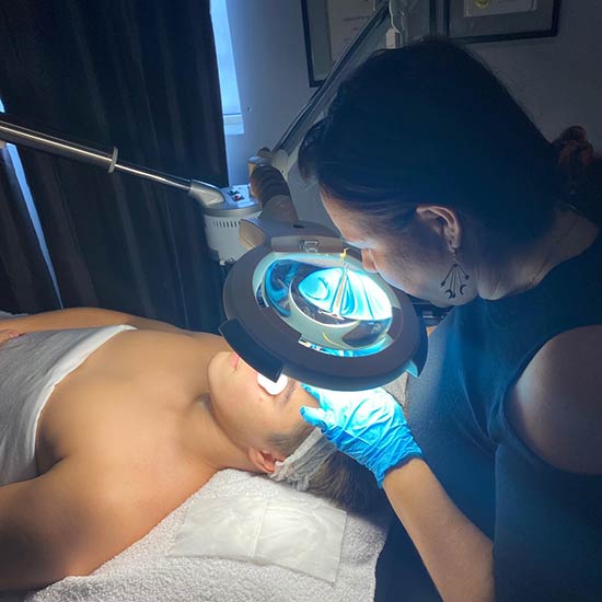 Blanca looking at skin under a lens for a facial